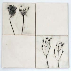 Beige Fliesen mit einer schwarzen Pflanze